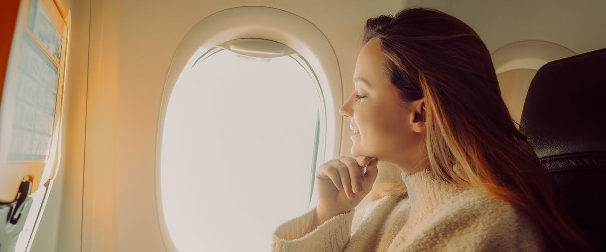 A traveling woman looking out of an airplane window A traveling woman looking out of an airplane window